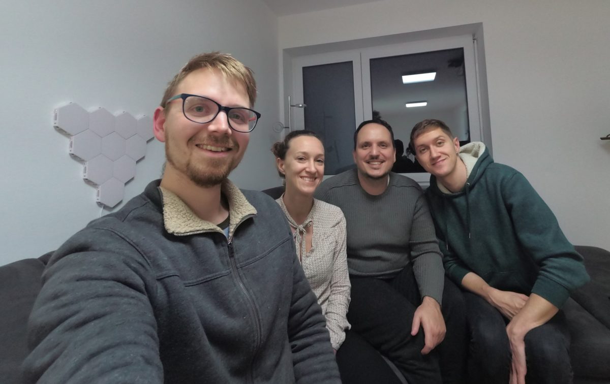 Team, 3 men, 1 woman, sitting in a room on a sofa