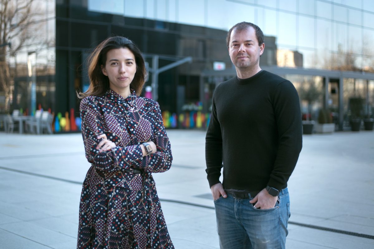 Woman (to the right) and man, both founders of the company, standing in front of a big building