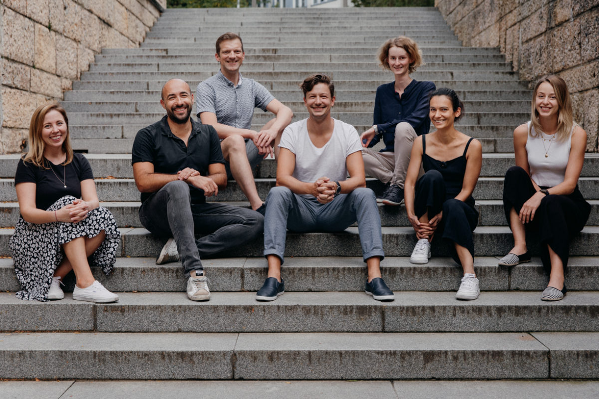 team, male and female, sitting on a staircase outside of a building