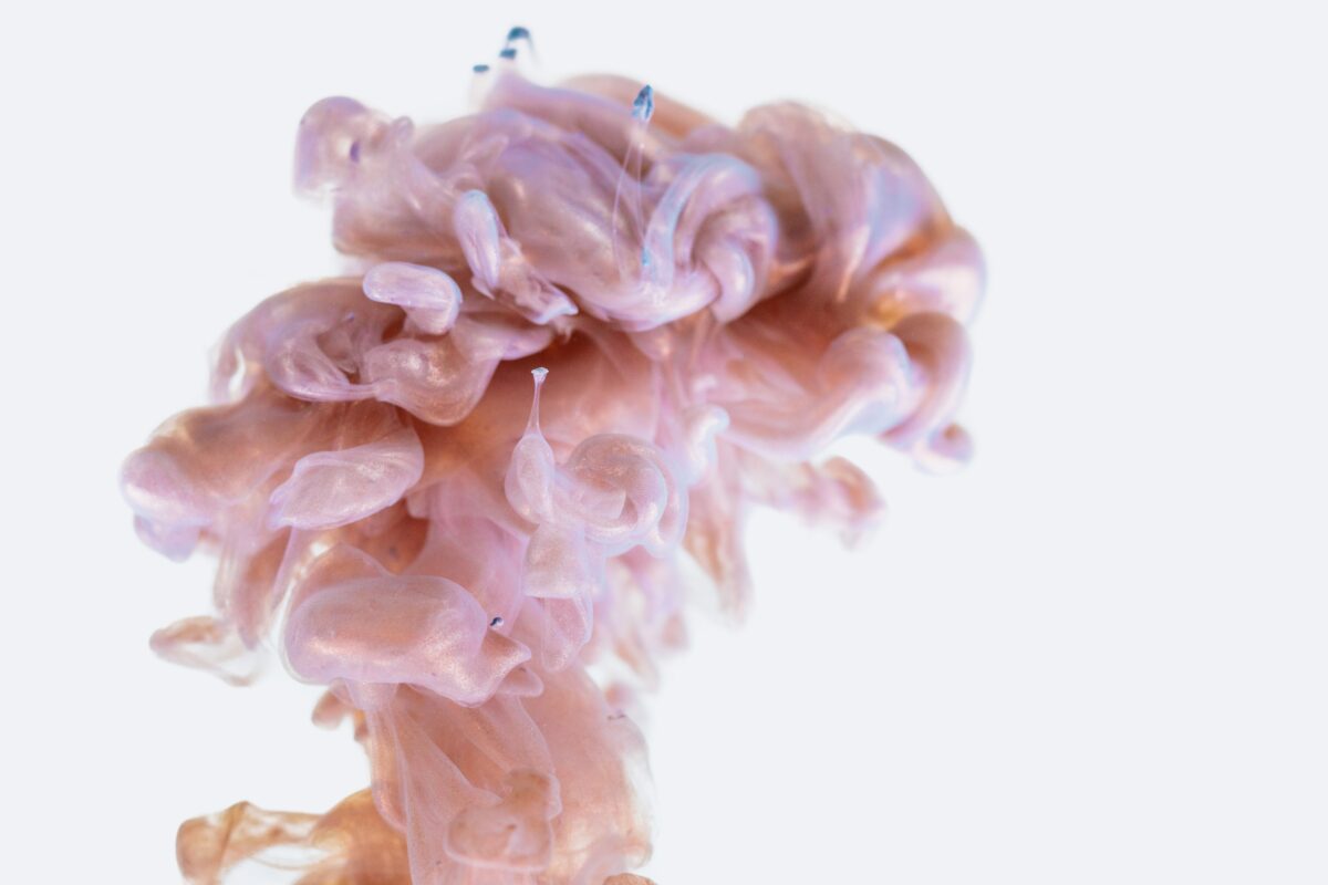 Pink color splashing and dissolving in water looking like the shape of a brain