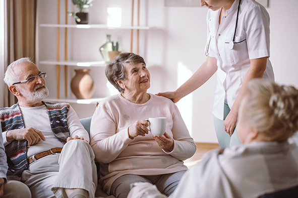 Senior lady talking with nurse and sitting with her elderly friends