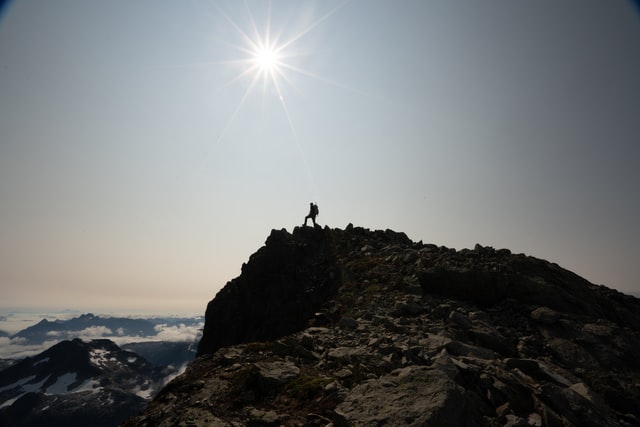 picture of man walking on the rim of a mountain and sun shining brightly