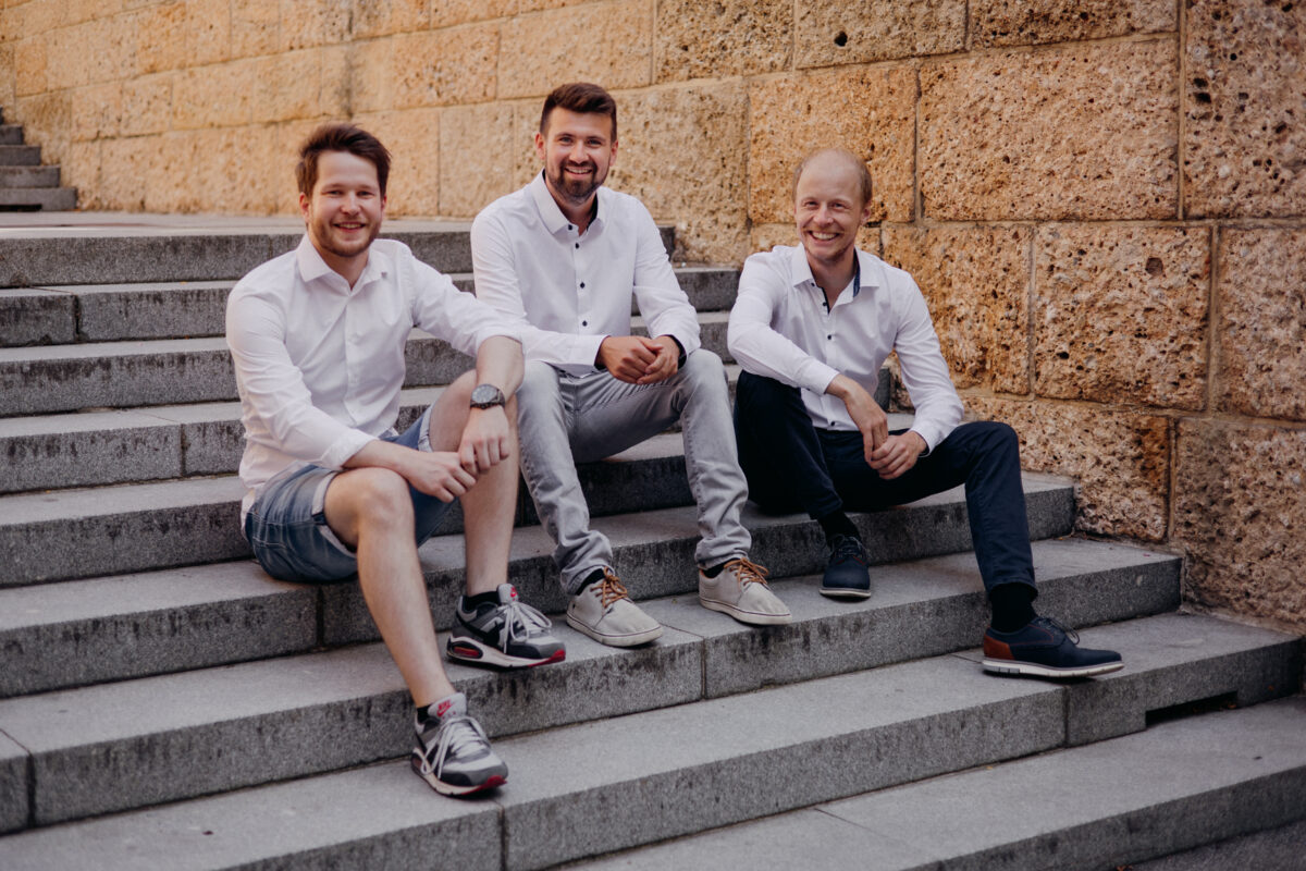 three men in white shirts sitting next to each other on a staircase outside