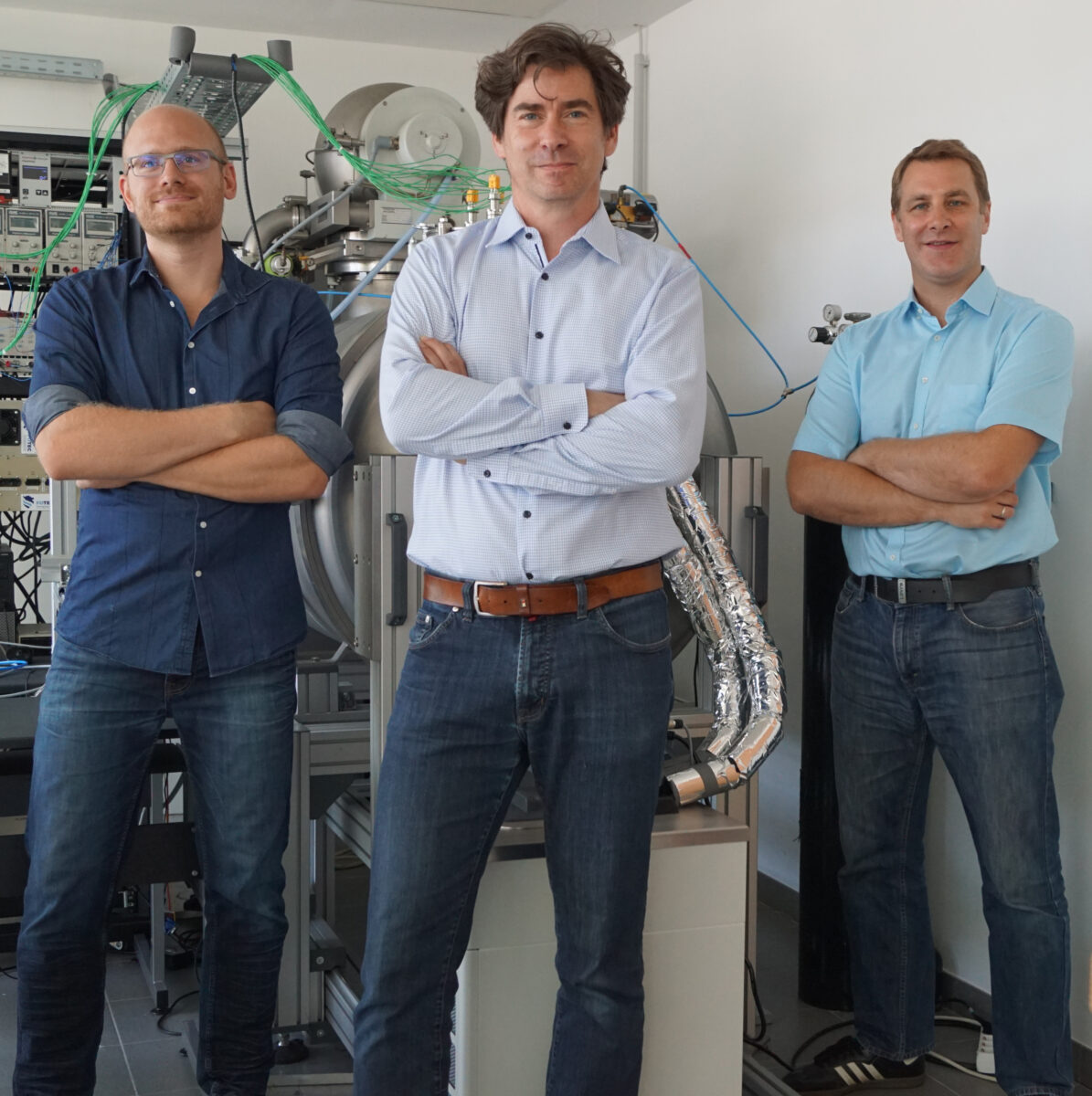 3 men with hands crossed in front of them standing in a room with technical equipment